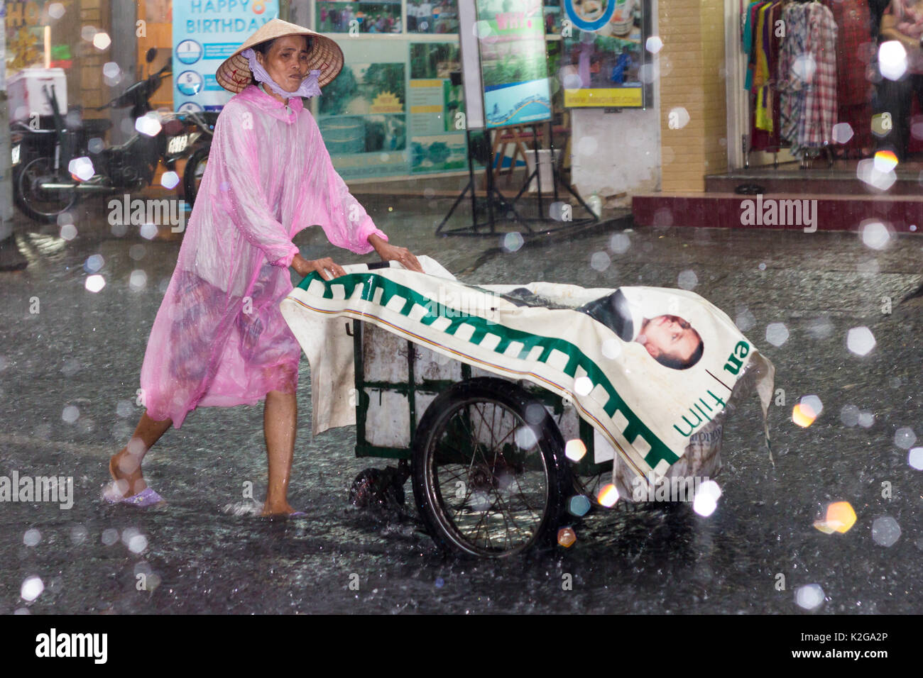 Une femme pousse son chariot à travers l'inondation et des pluies torrentielles sur Bui Vien street, Ho Chi Minh Ville (Saigon), Vietnam Banque D'Images