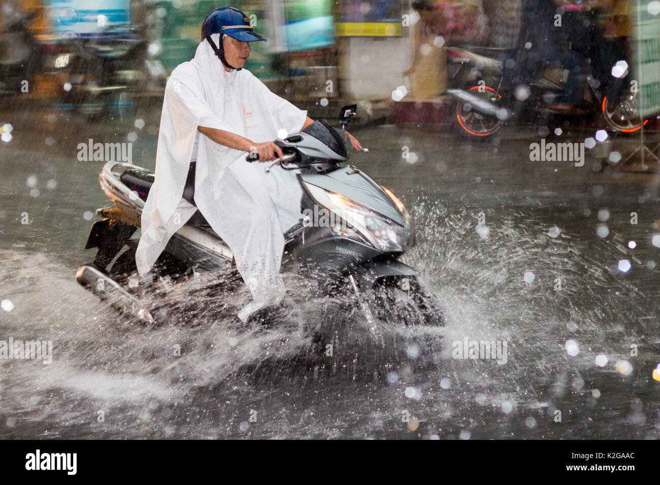 Les lecteurs de l'homme en moto à travers l'inondation et des pluies torrentielles sur Bui Vien street, Ho Chi Minh Ville (Saigon), Vietnam Banque D'Images