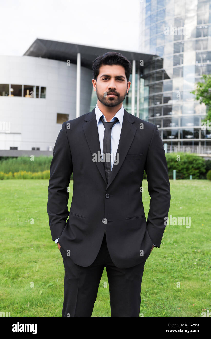 L'arabe est de l'Inde, serious businessman ou travailleur en costume noir  avec une cravate et chemise avec barbe, debout devant un immeuble de  bureaux avec des mains dans Photo Stock - Alamy