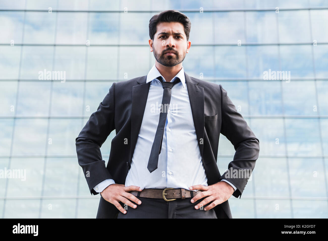 L'arabe serious businessman ou travailleur en costume noir avec une cravate  et chemise avec barbe, debout devant un immeuble de bureaux sur l'herbe  verte en été 24 Photo Stock - Alamy