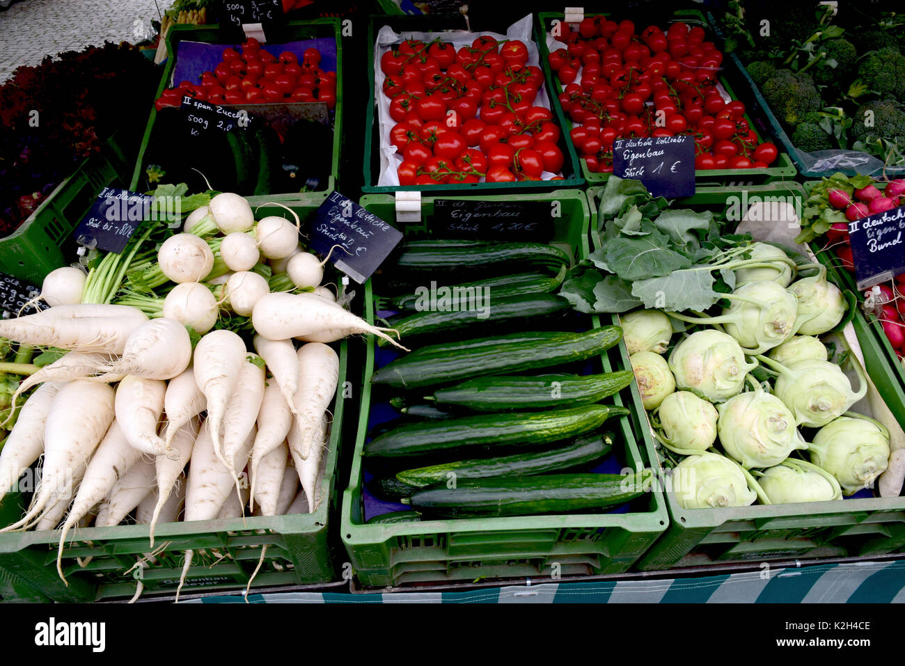 Échoppe de marché offrant différentes sortes de tomates dans l'arrière-plan et à l'avant de gauche à droite : rabiole, concombre, Turnio allemand Banque D'Images