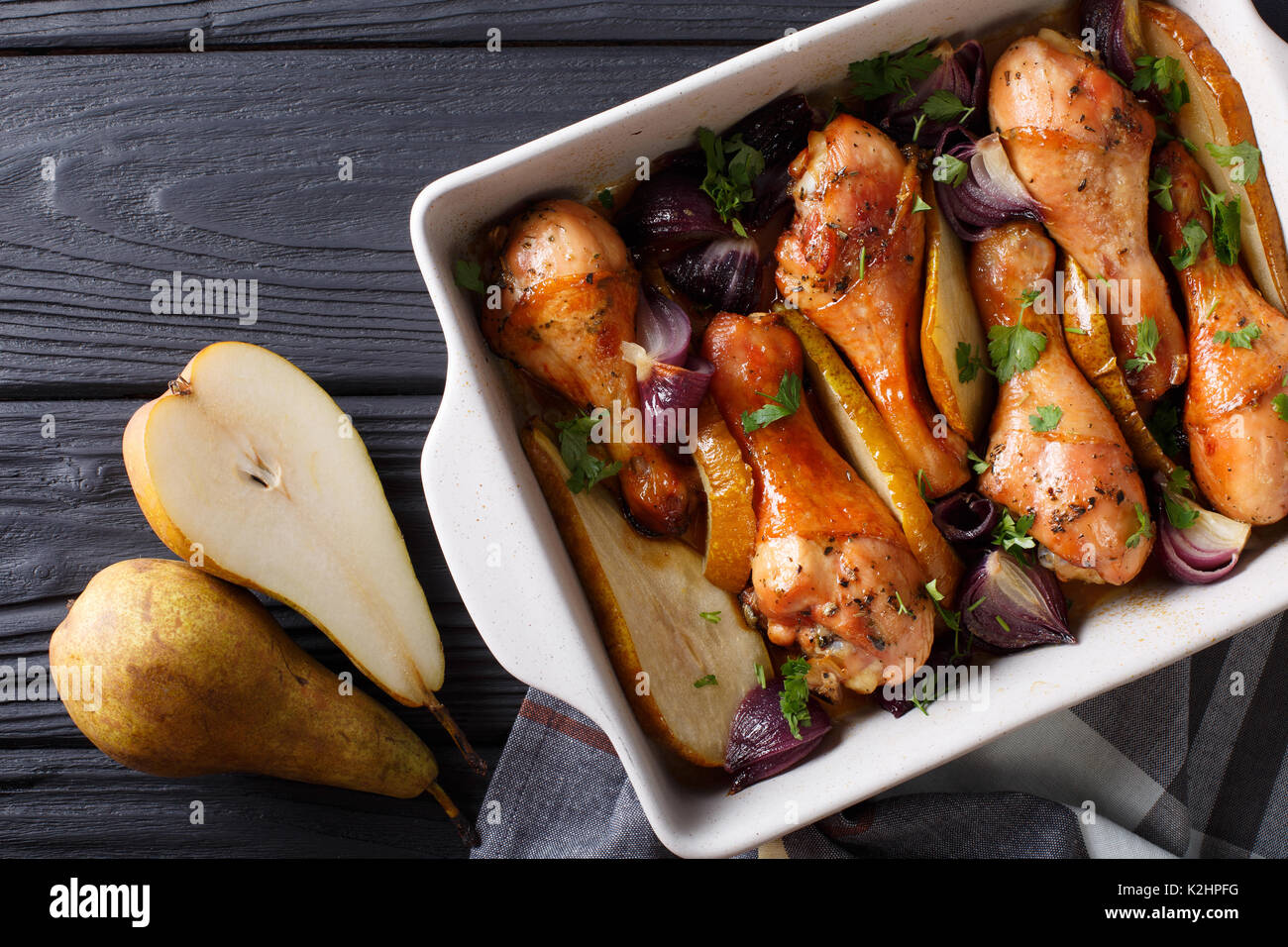 Automne : des aliments cuits au four pilons de poulet avec l'oignon rouge, les poires et les herbes close up dans un plat pour la cuisson. Vue de dessus d'au-dessus de l'horizontale Banque D'Images