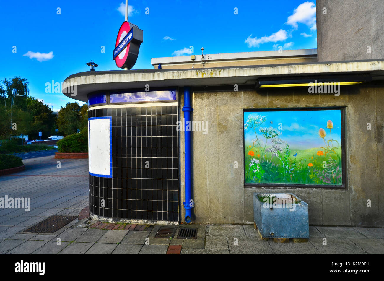La station de métro Central line Wanstead d'une murale de campagne sur le mur. Un vieux réservoir d'eau est utilisée comme un semoir. Banque D'Images