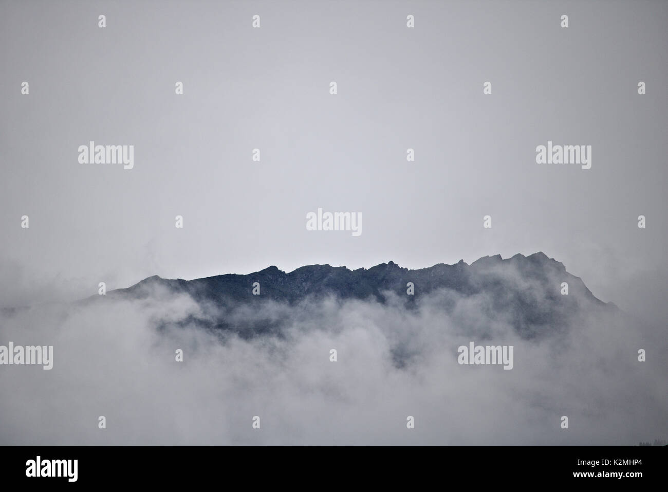 La crête de la montagne lointaine à peine visible au-dessus des nuages et de la brume Banque D'Images