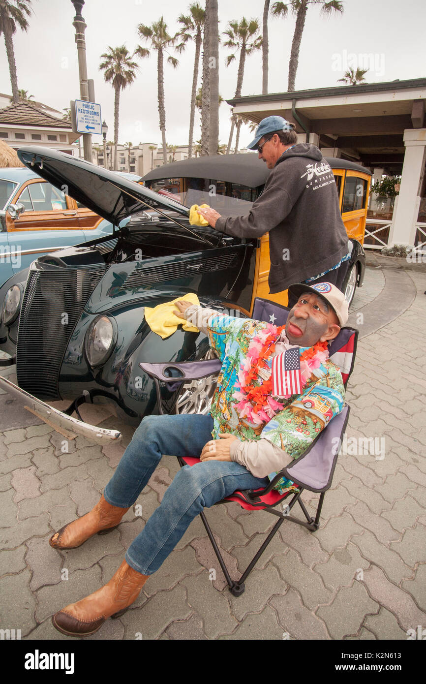 Une voiture classique collector polit ses 1947 Ford 'woodie' station wagon sur l'affichage à une exposition de voiture au centre-ville de Huntington Beach, CA. Remarque mascot mannequin surnommé 'Homer Huggins.' Banque D'Images