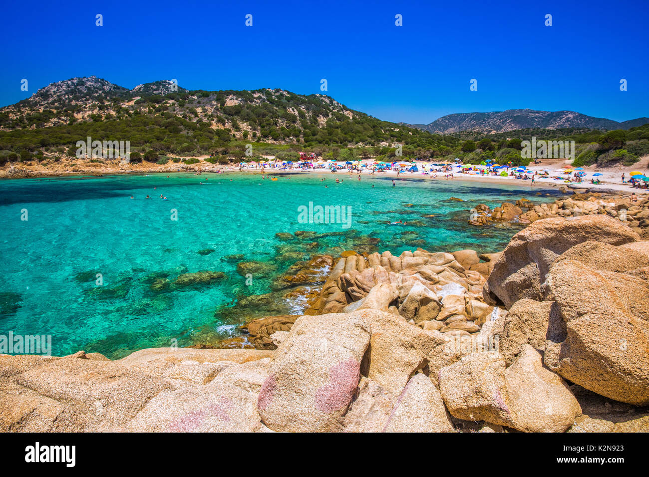 Plage de Cala Cipolla avec pierres rouges et d'azur de l'eau claire, Chia, Sardaigne, Italie. Banque D'Images