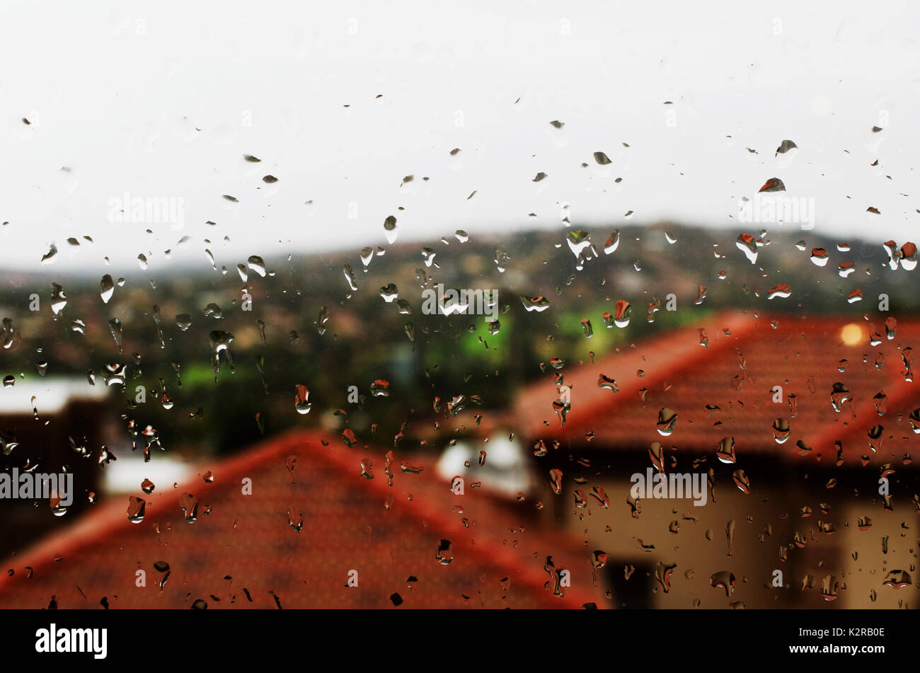 Verre avec des gouttes de pluie sur un fond de maisons aux toits rouges, selective focus, l'arrière-plan Banque D'Images