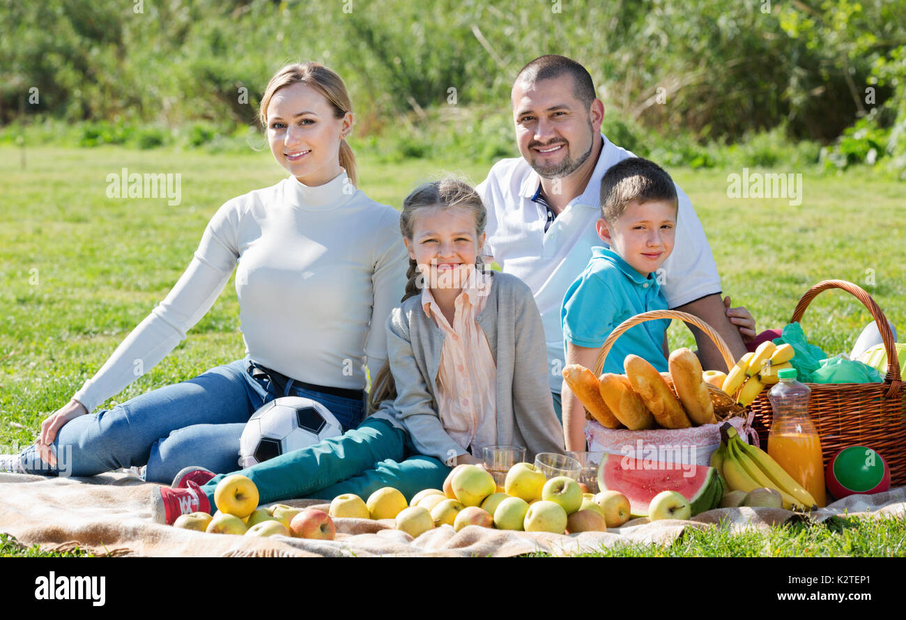 Smiling family de quatre un pique-nique en plein air dans un beau temps Banque D'Images