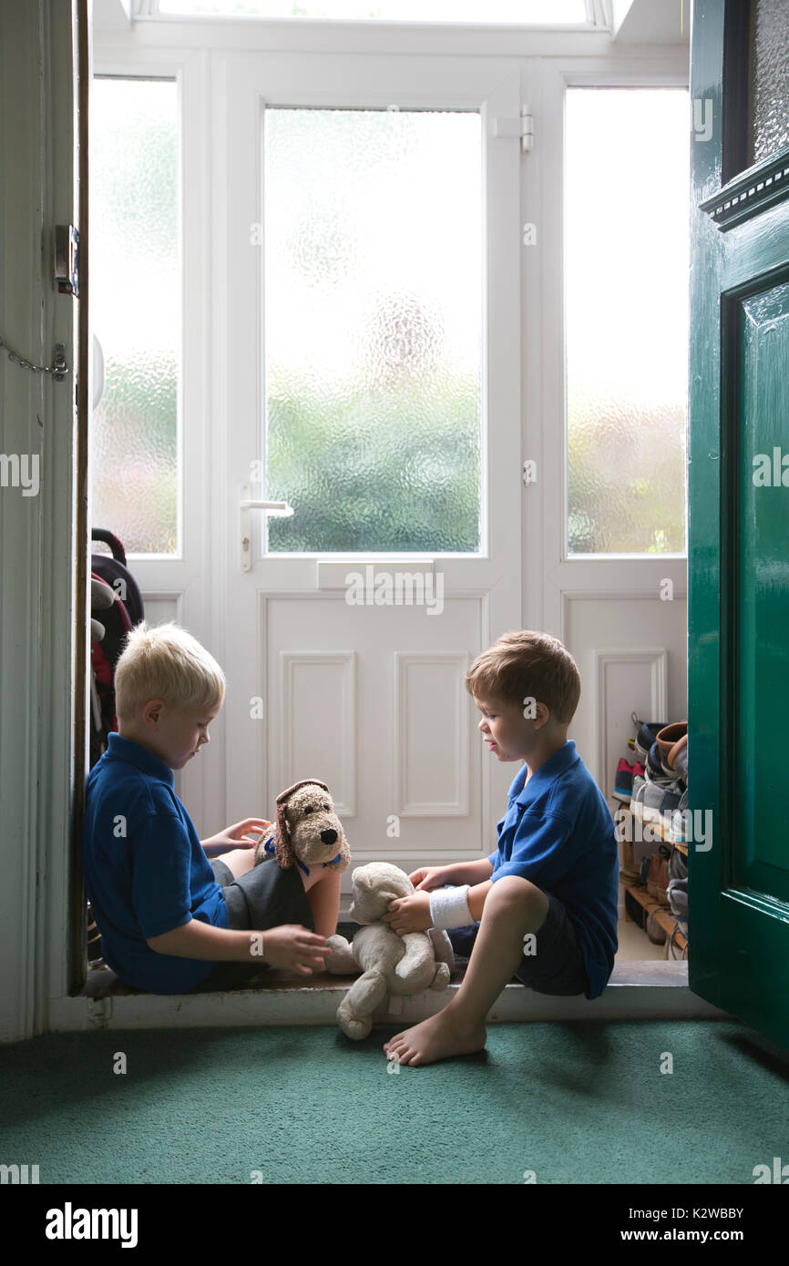 3 ans et 6 ans garçons assis dans un quartier résidentiel de la porte habillé en uniforme prêt à retourner à l'école, London, England, UK Banque D'Images