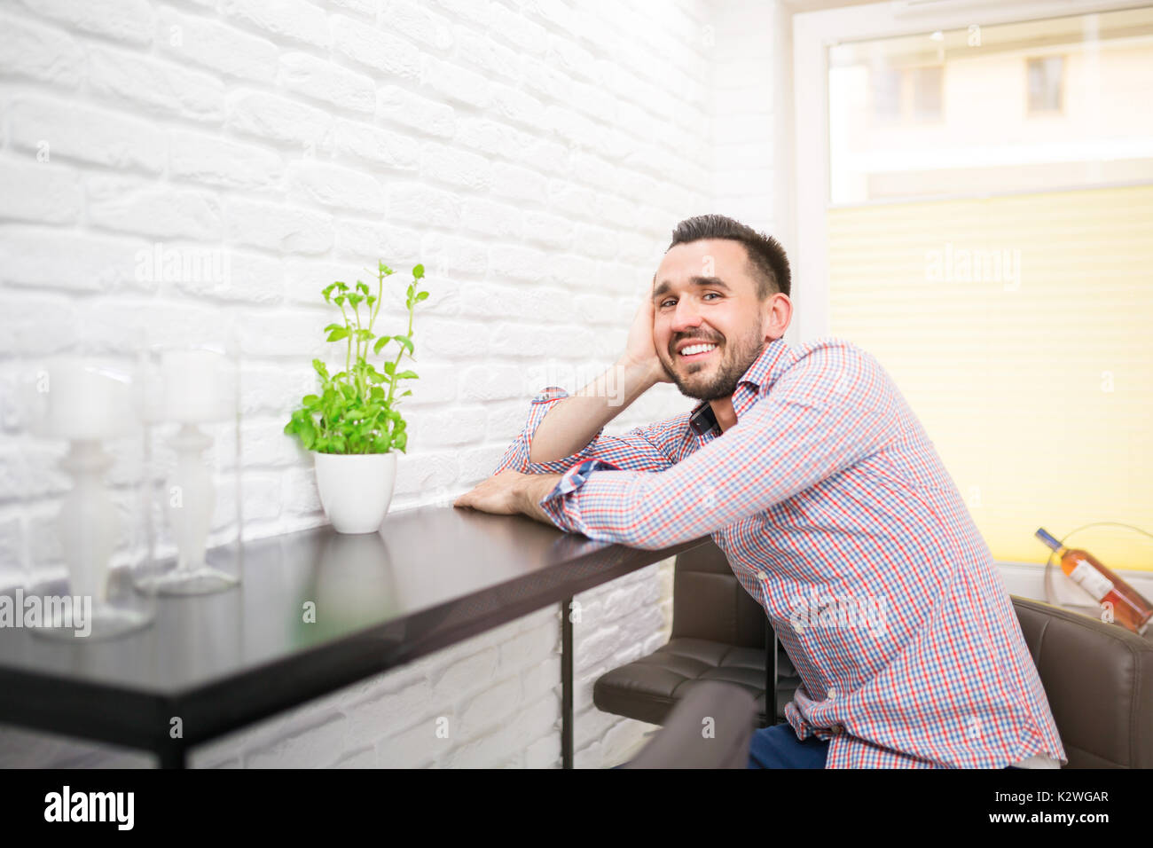 Jeune homme assis dans la cuisine et smiling Banque D'Images