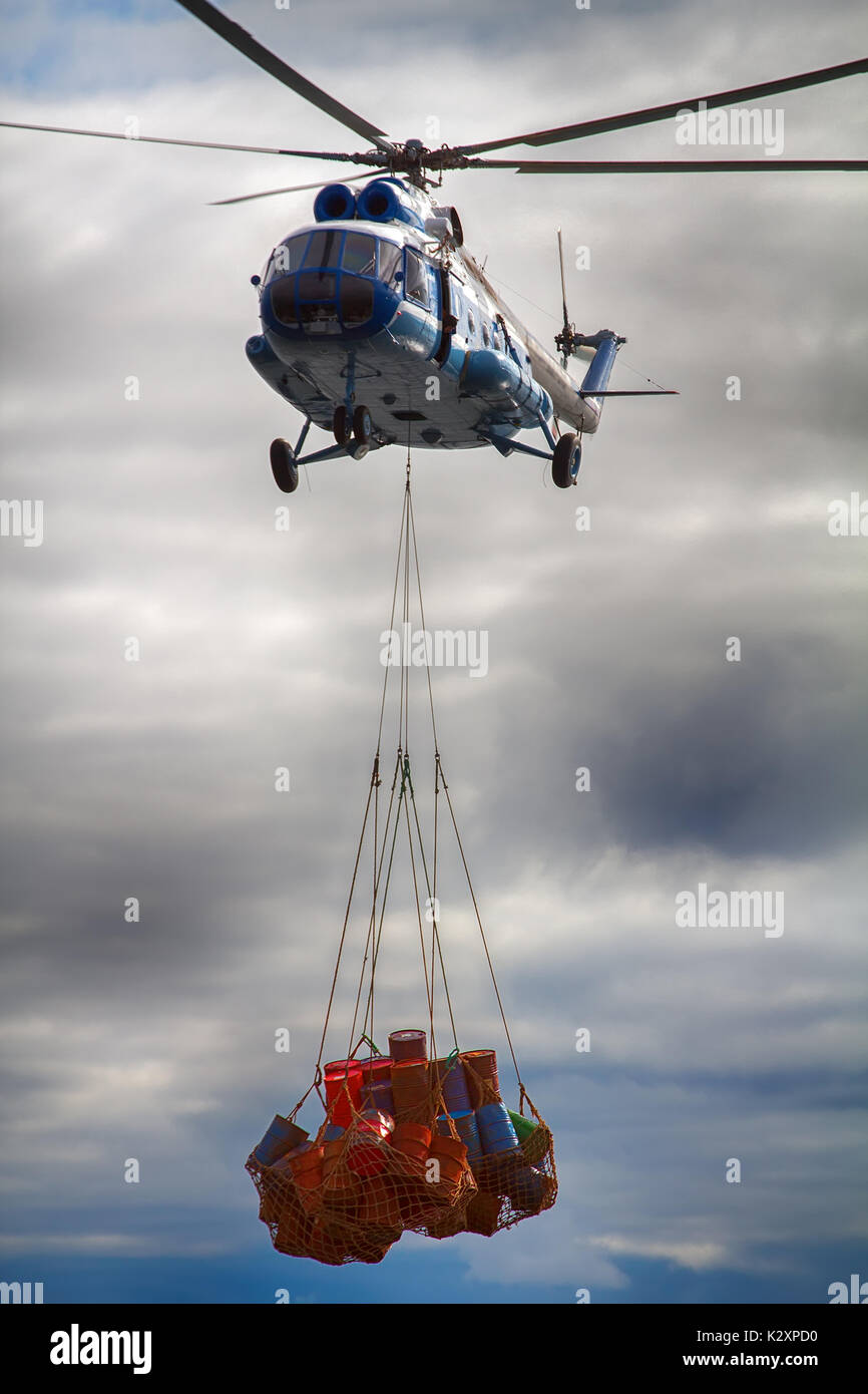 Le fret et le travail de l'aviation, du fret air service, ascenseur, hélicoptère. Porte hélicoptère sling (mesh) avec corde de barils de métal vide Banque D'Images