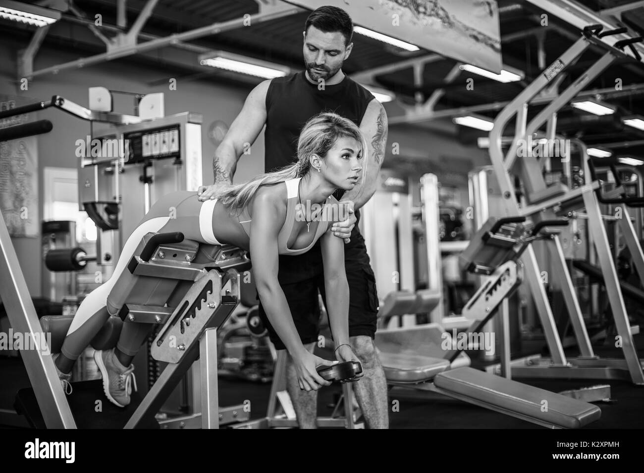 Fille sportive faisant des exercices de poids corporel avec l'aide de son entraîneur personnel à la salle de sport. Banque D'Images