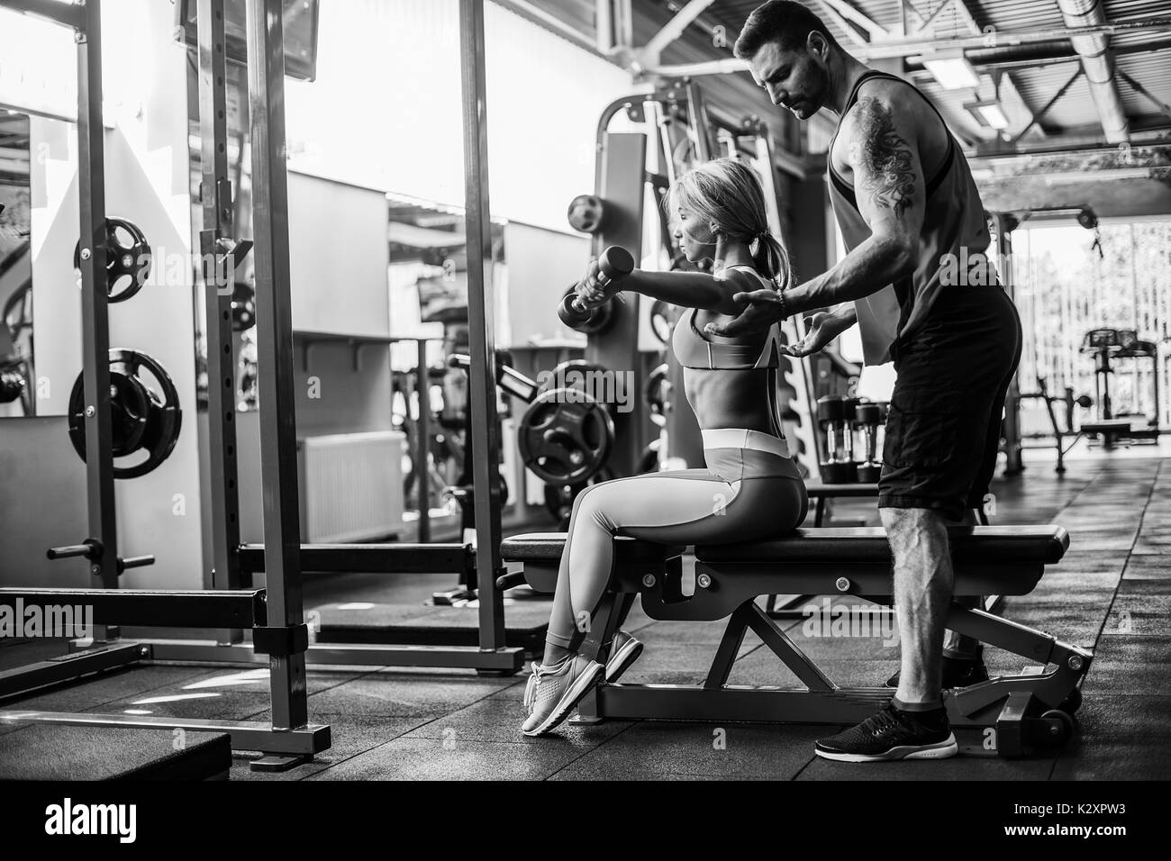 Fille sportive faisant des exercices de poids corporel avec l'aide de son entraîneur personnel à la salle de sport. Banque D'Images