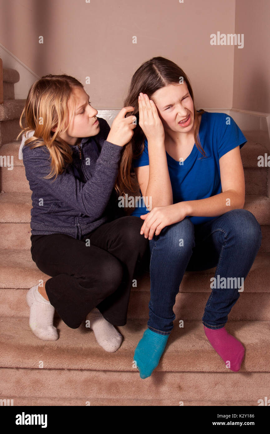 Jeune fille tirant ses soeurs les cheveux. Banque D'Images