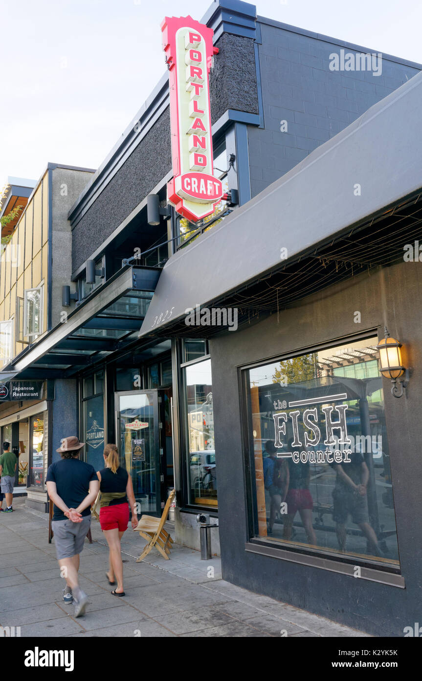 Jeune couple en passant devant l'artisanat Portland pub et le comptoir de poissons sur Main Street, Vancouver, BC, Canada Banque D'Images