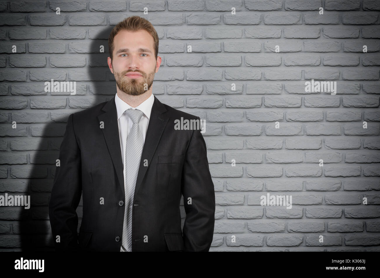 Beau elegant businessman en fonction de copie espace, mur de brique gris en arrière-plan Banque D'Images