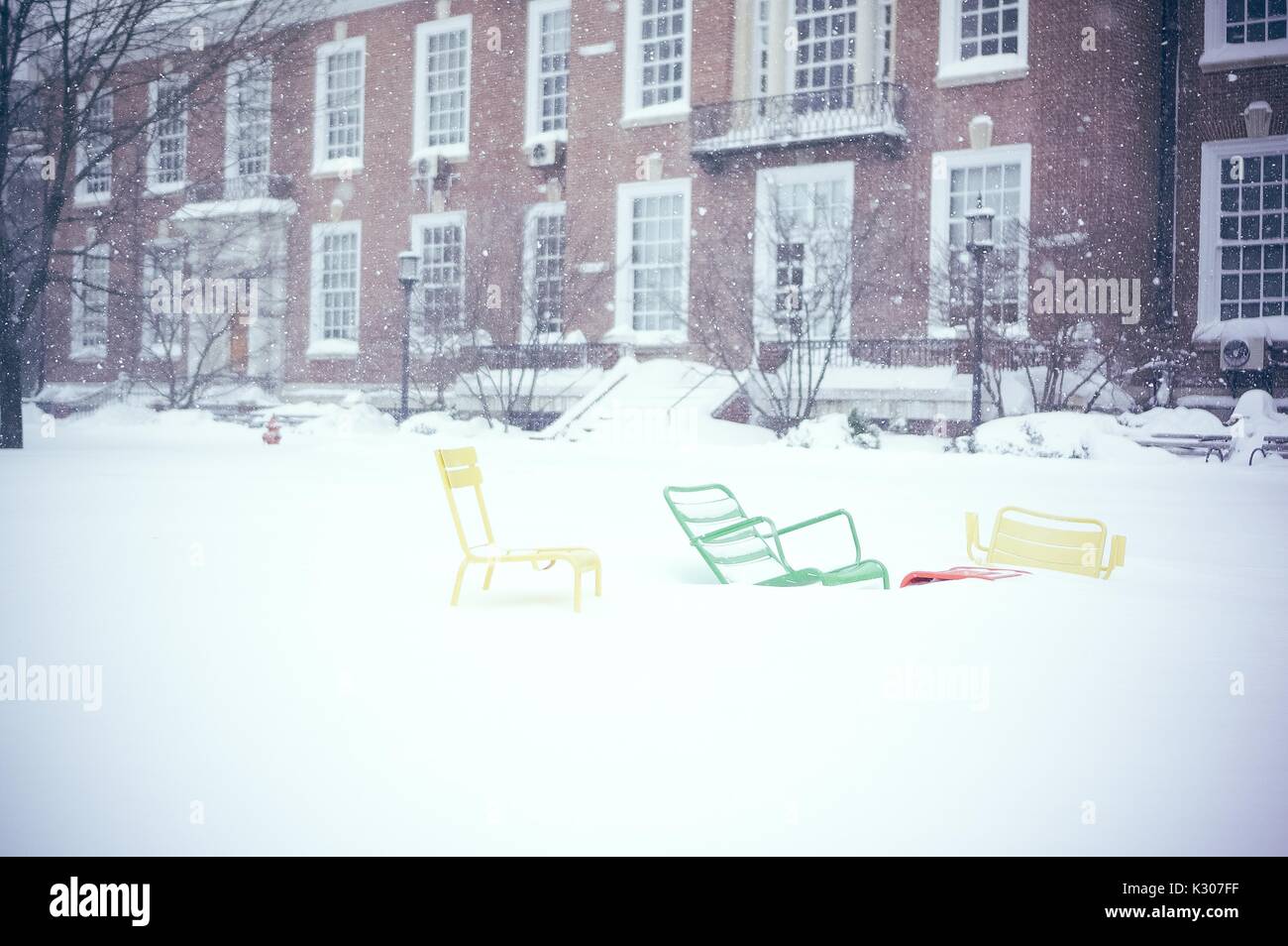 Trois chaises colorées reposer à couvert à trois pieds de neige en face d'un bâtiment en brique sur un quad neige à la Johns Hopkins University, Baltimore, Maryland, 2016. Banque D'Images