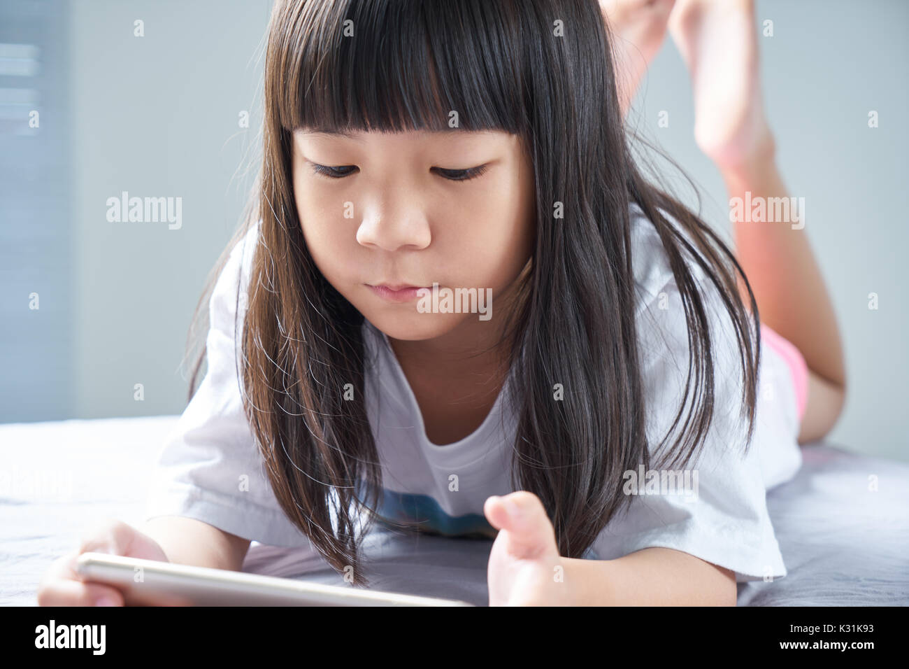 Peu de Chinois asiatique girl using smartphone et couché sur le lit . Banque D'Images