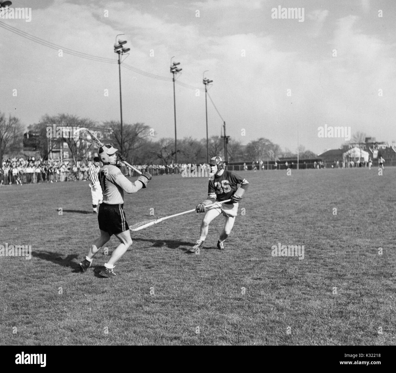 Sépia photographie d'action au cours d'un match de crosse pour hommes à l'Université Johns Hopkins, avec co-JHU légende Byron Forbush nombre 47 prépare à passer le ballon à un coéquipier pendant qu'un joueur adverse garde son coup avec son bâton, un comité permanent de l'arbitre a proximité, Baltimore, Maryland, juin, 1951. Banque D'Images