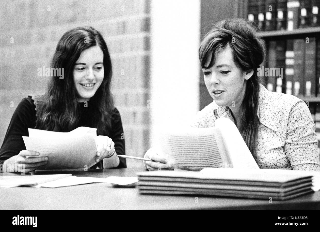 Deux étudiants diplômés de l'Université Johns Hopkins, sourire en examinant un texte ensemble à une table d'étude à la bibliothèque, Baltimore, Maryland, 1975. Banque D'Images