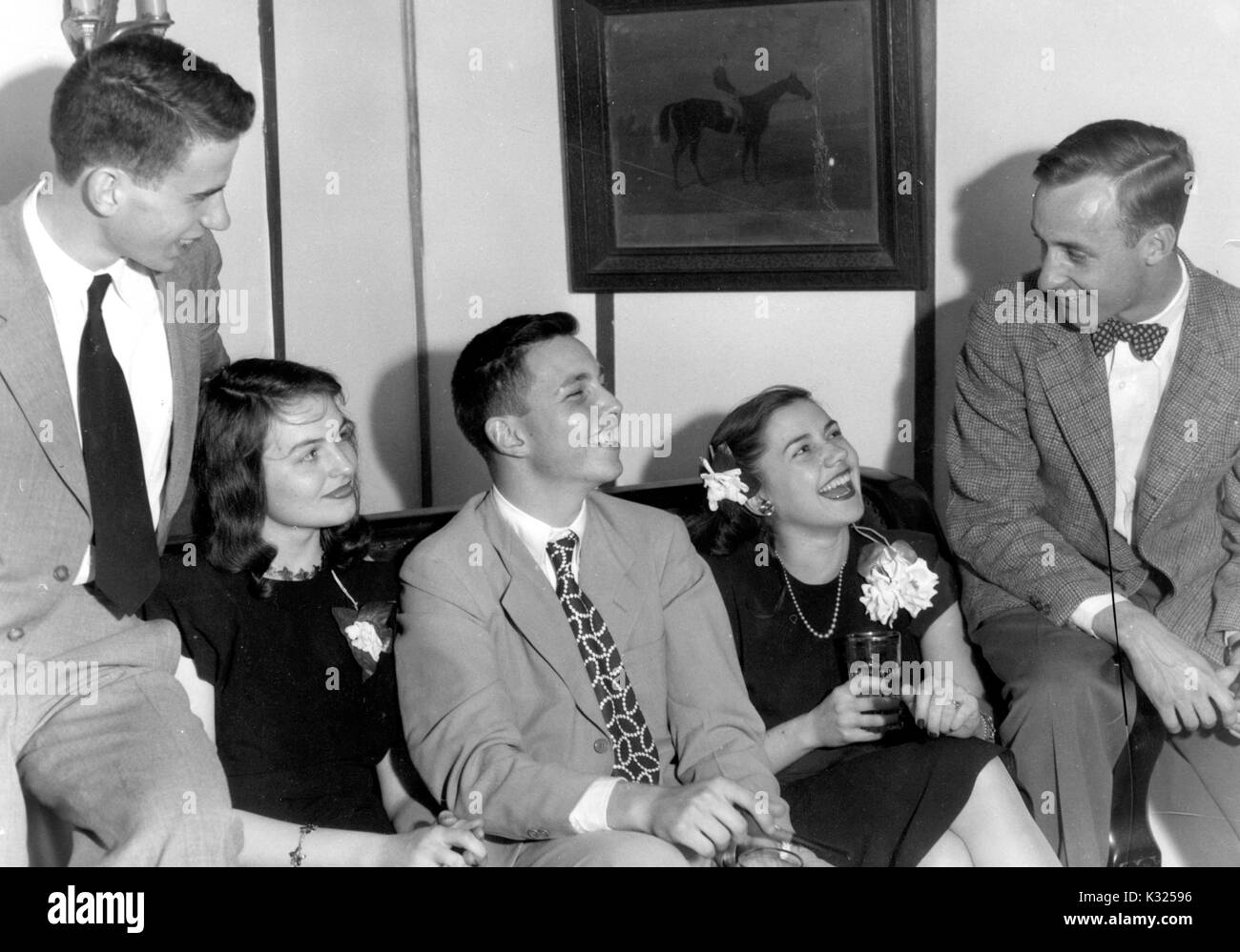 Lors d'une fête organisée par la fraternité Phi Delta à l'Université Johns Hopkins, les frères lounge sur un canapé dans un groupe, portant des costumes à côté de leurs copines dans les robes et les corsages, tout le monde de sourire et de boire des boissons à partir de verres, dans une fraternité house hors-campus, Baltimore, Maryland, 1947. Banque D'Images