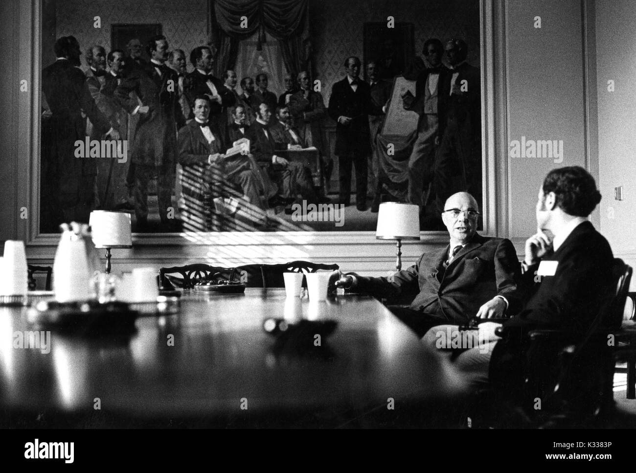 Portrait candide de l'Université Johns Hopkins, président Milton S. Eisenhower (à gauche) assis à une grande table et de parler à un chiffre non identifié au cours de la Milton S. Eisenhower 1971 Symposium, une série de conférences de l'Université John Hopkins, à Baltimore, Maryland, 1971. Banque D'Images