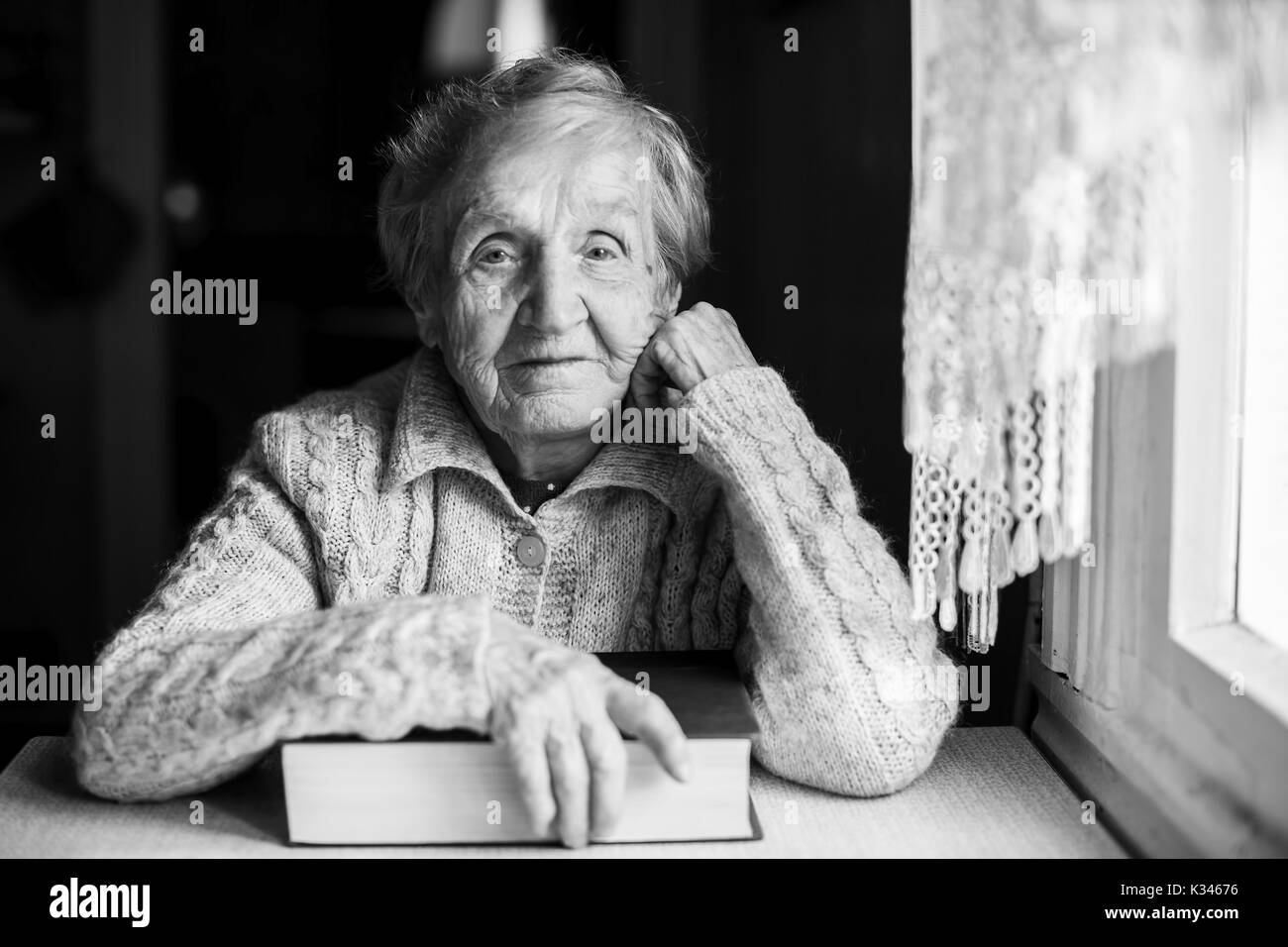 Une femme âgée avec un livre fermé à la table. Banque D'Images