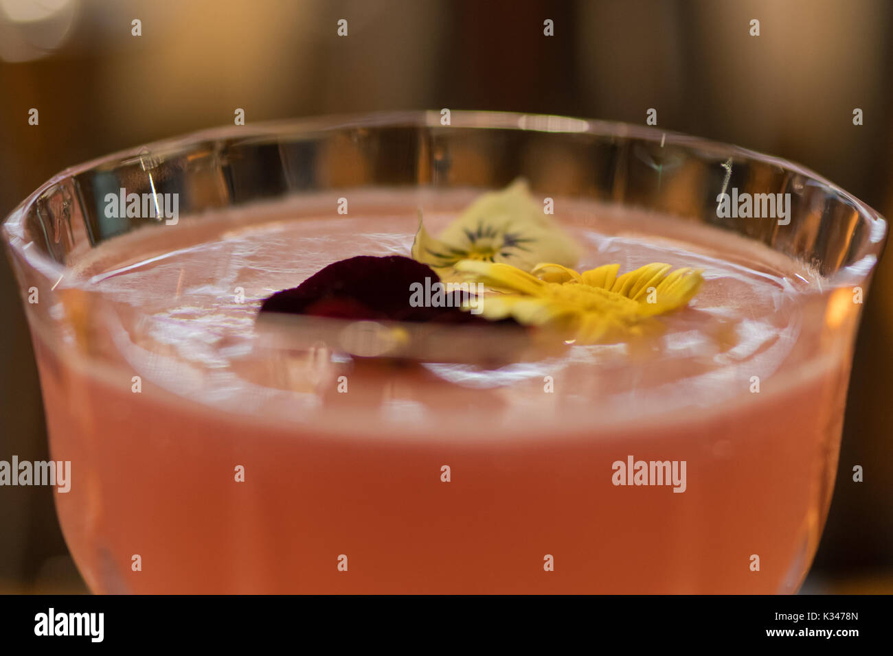 Cocktail rose garni de fleurs. Boisson alcoolisée montrant le détail de fleurs en verre flottant dans marguerite Banque D'Images