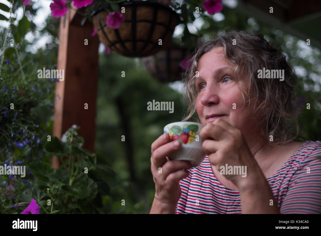 Senior woman in green garden avec des fleurs dans les mains Banque D'Images