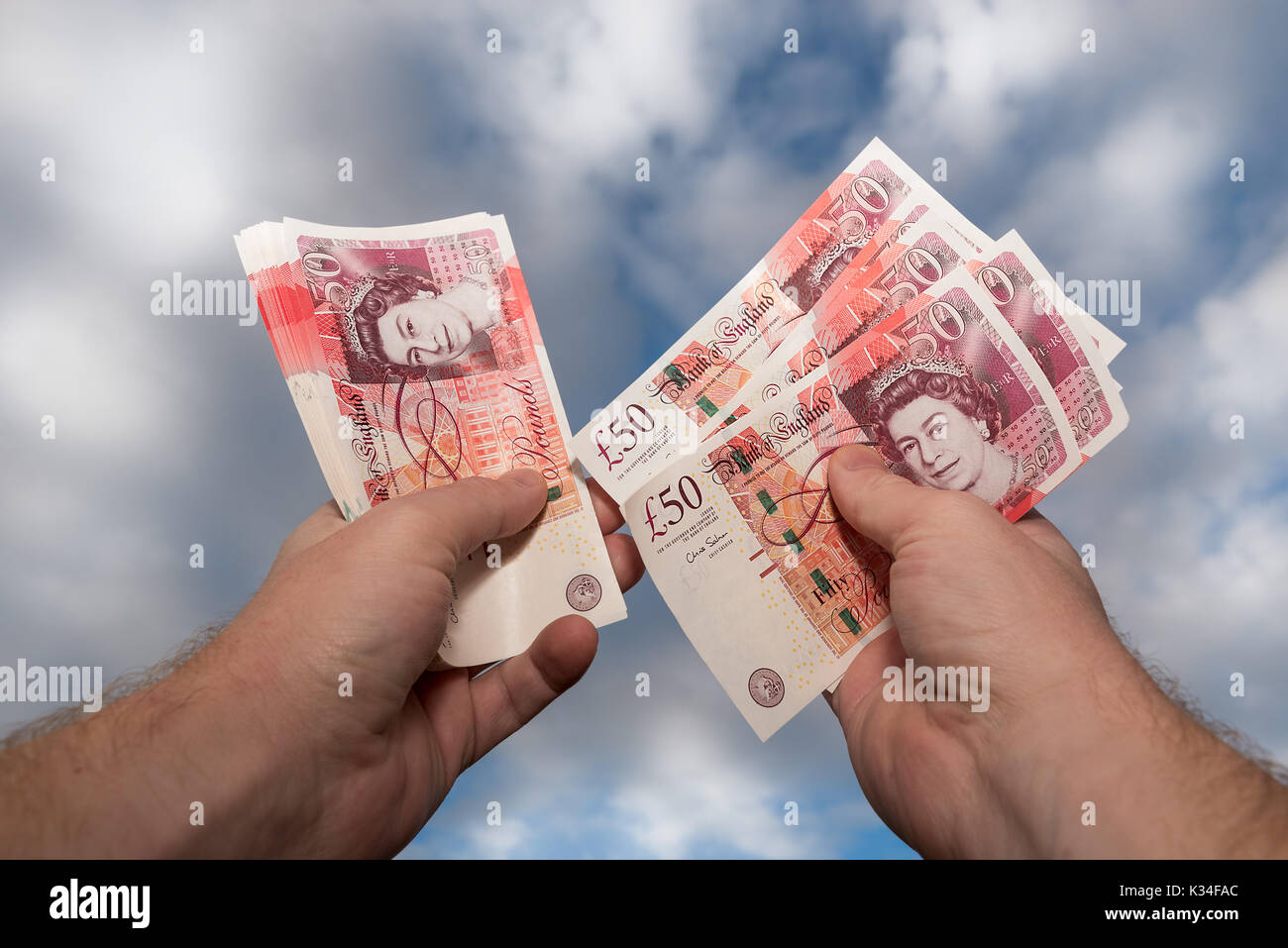 Paire de mains comptant nouveau style GBP £50 remarques sterling avec ciel bleu et fond de nuage. Banque D'Images