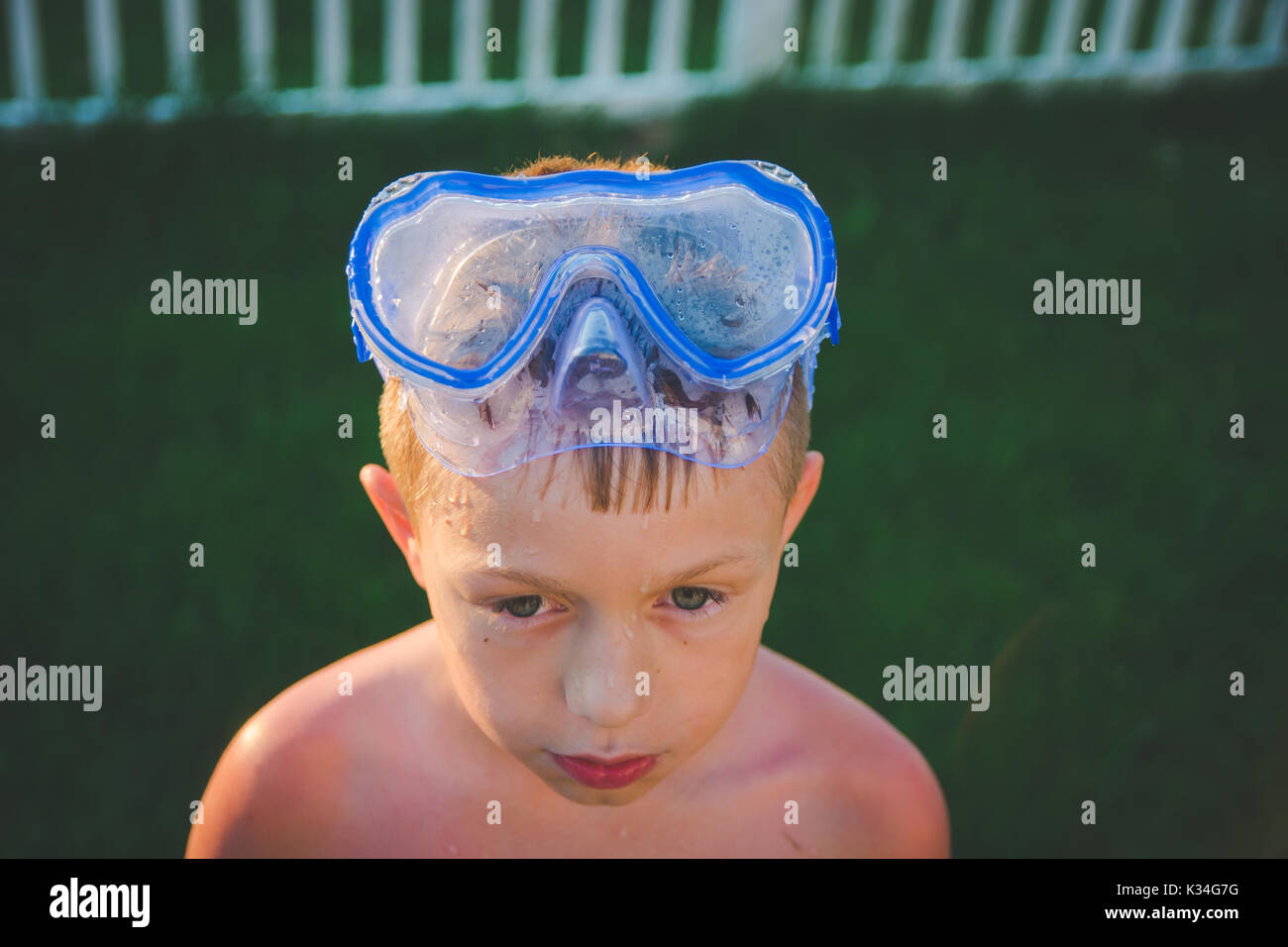 Un garçon porte un masque de plongée sur la tête pendant l'été alors que le soleil brille sur lui. Banque D'Images
