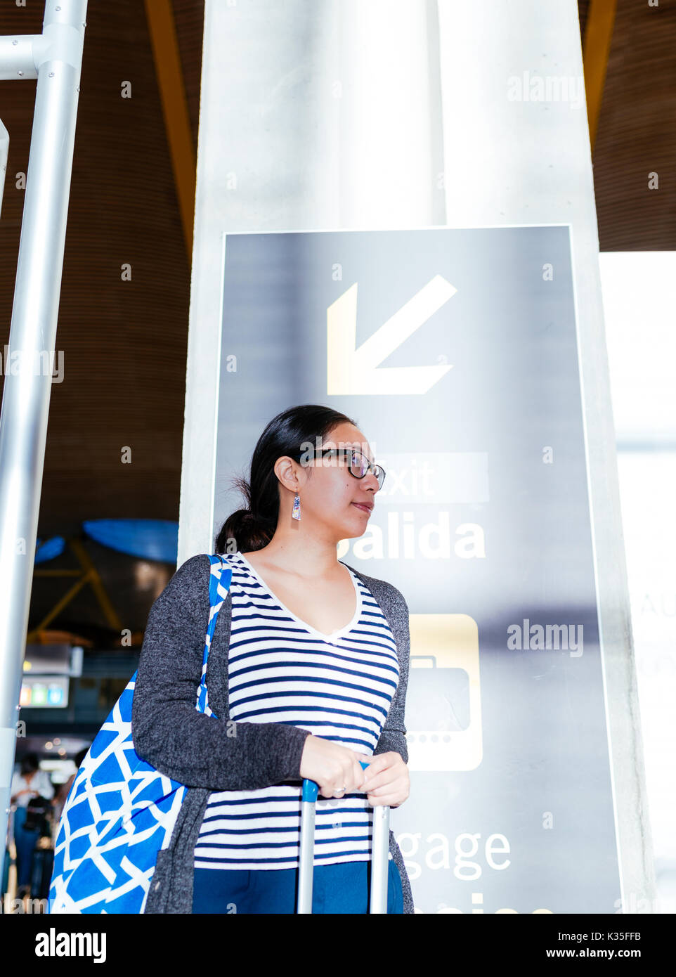 Femme attendant à une colonne dans l'aéroport Banque D'Images