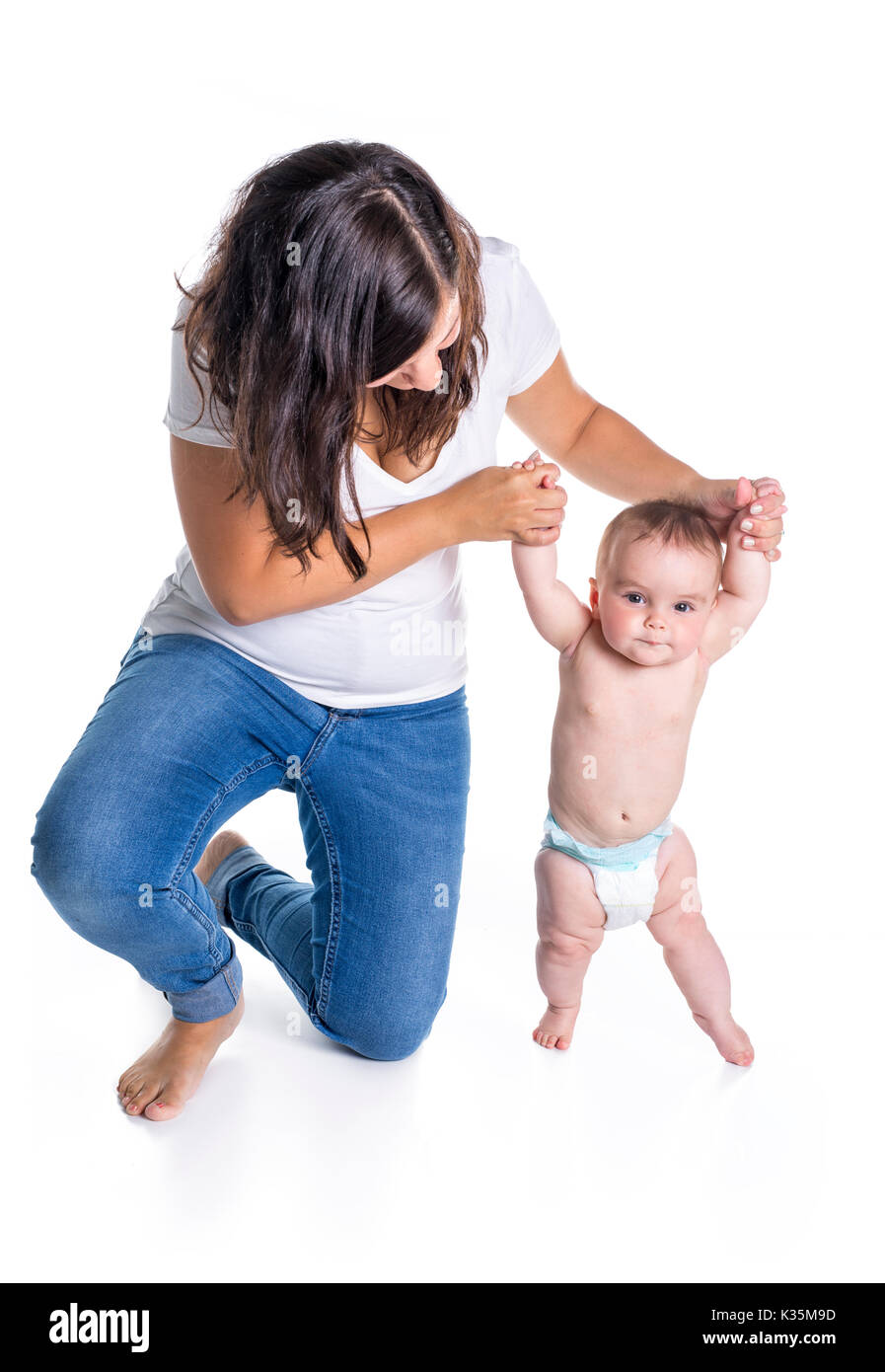 Les premiers pas de bébé avec la mère de l'aide sur fond blanc Banque D'Images