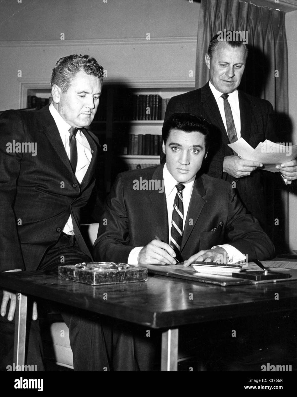 L-R VERNON PRESLEY, ELVIS PRESLEY ET MARK KING Elvis signant l'un des 50 chèques faits à Memphis de bienfaisance. Banque D'Images