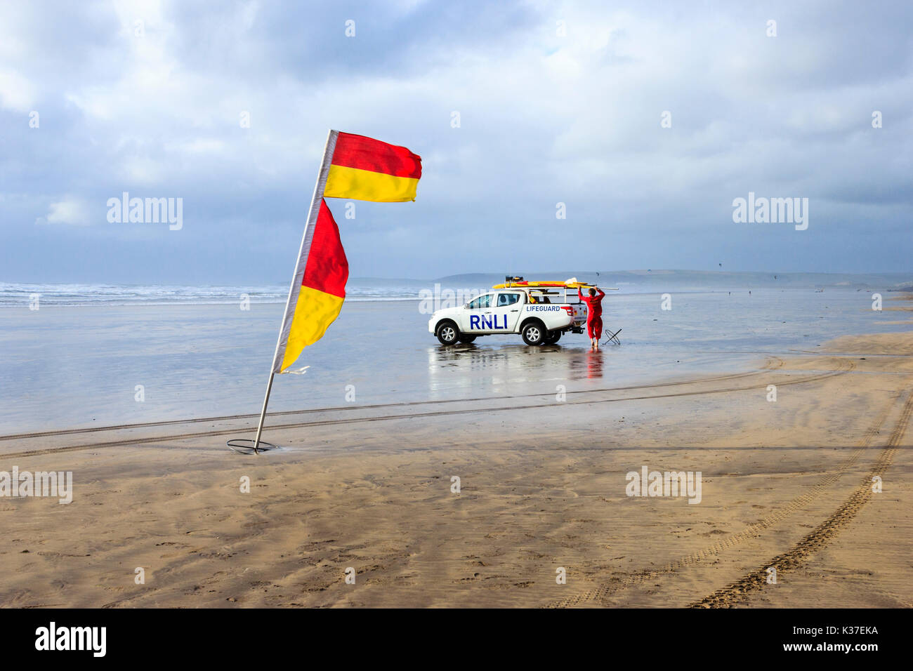 Un indicateur d'alerte rouge et jaune et sauveteur RNLI avec véhicule sur la plage de sable à Westward Ho ! À marée basse sous un ciel couvert et venteux jour d'été Banque D'Images