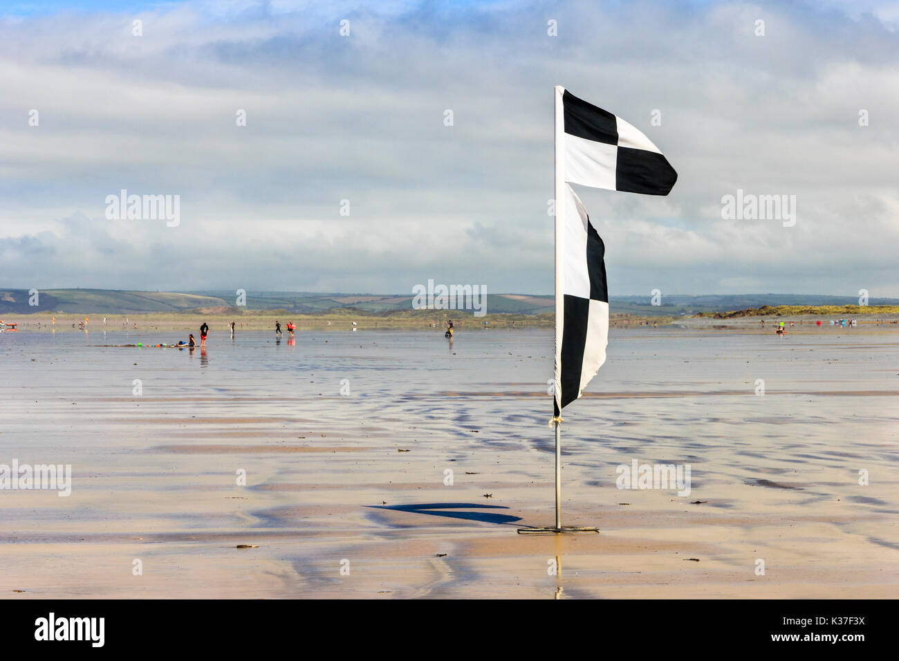 Avertissement en damier noir et blanc drapeau sur la plage de sable à marée basse, Westward Ho !, Devon, England, UK Banque D'Images