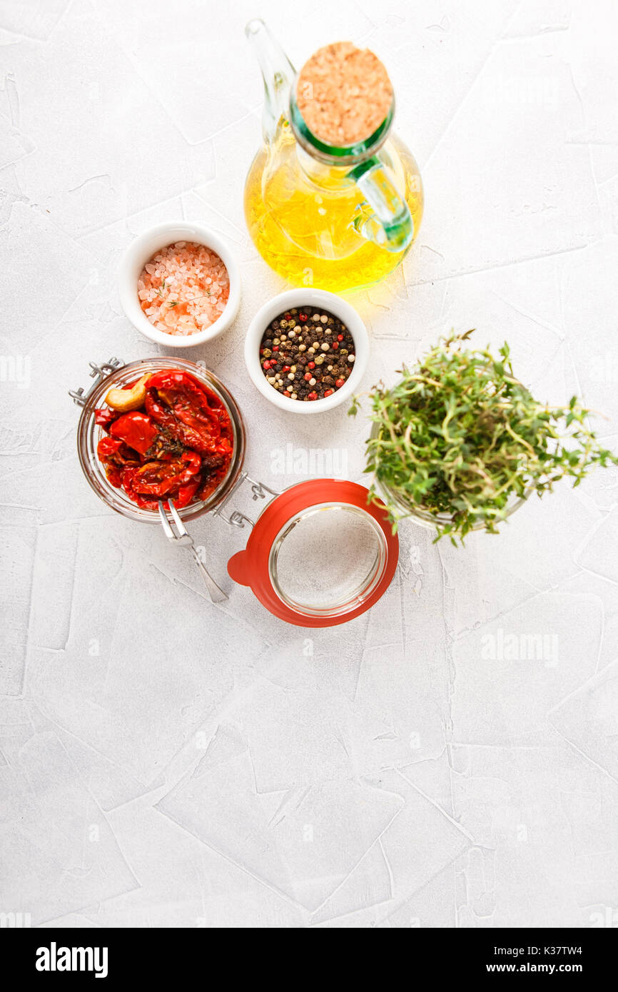 Pot en verre de tomates séchées, huile d'olive, le thym et le sel rose de poivre. Vue d'en haut Banque D'Images