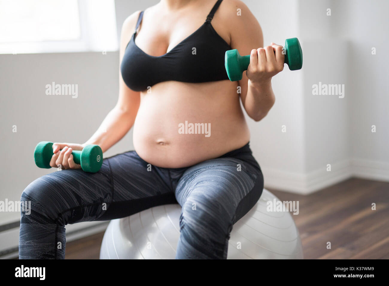 Femme enceinte avec haltères d'entraînement pour rester actif Banque D'Images