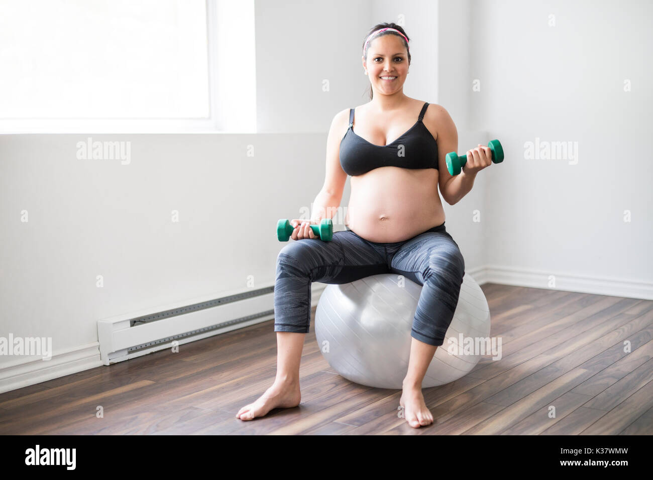 Femme enceinte avec haltères d'entraînement pour rester actif Banque D'Images