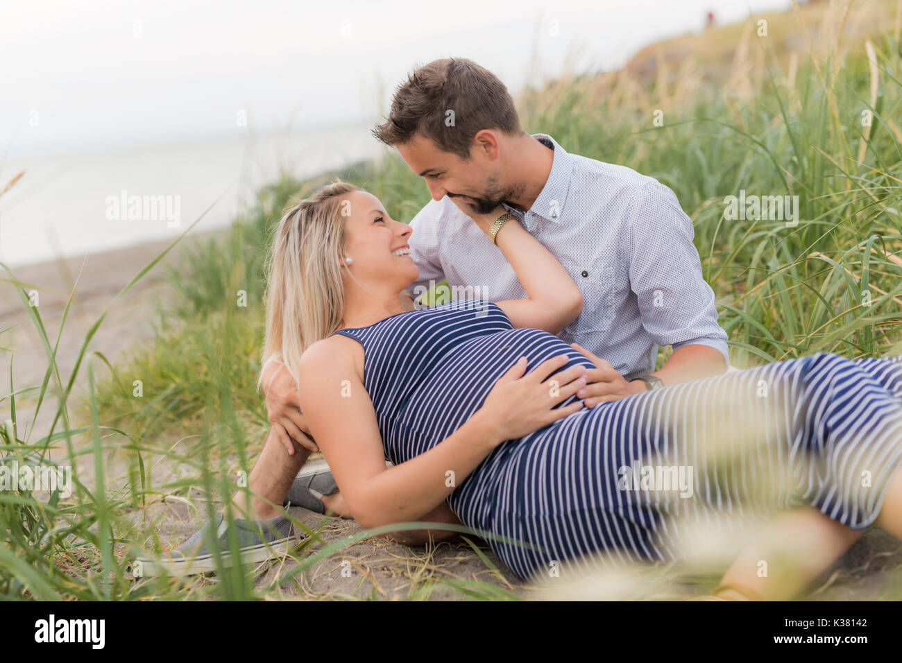 Femme enceinte à plage avec mari s'amusant Banque D'Images