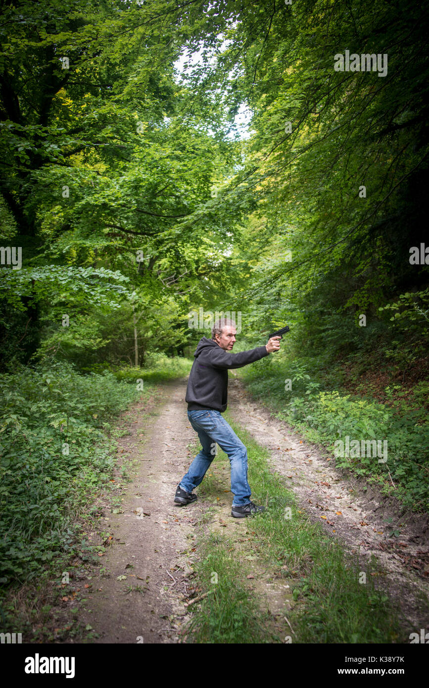 Homme pointant un pistolet portant un hoodie Banque D'Images