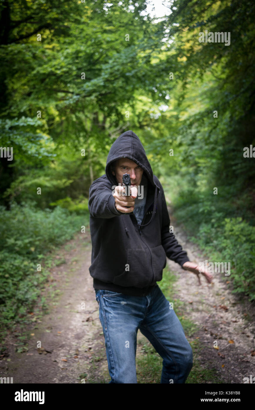 Homme pointant un pistolet portant un hoodie Banque D'Images