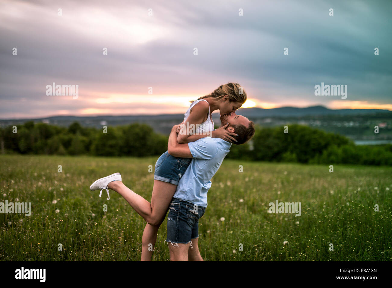 Jeune couple pour le coucher du soleil dans la prairie Banque D'Images