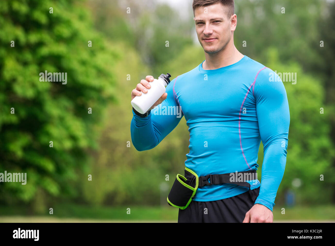 Une photo de jeune homme bien bâti, tenue sportive dans l'eau potable de bidon. Banque D'Images