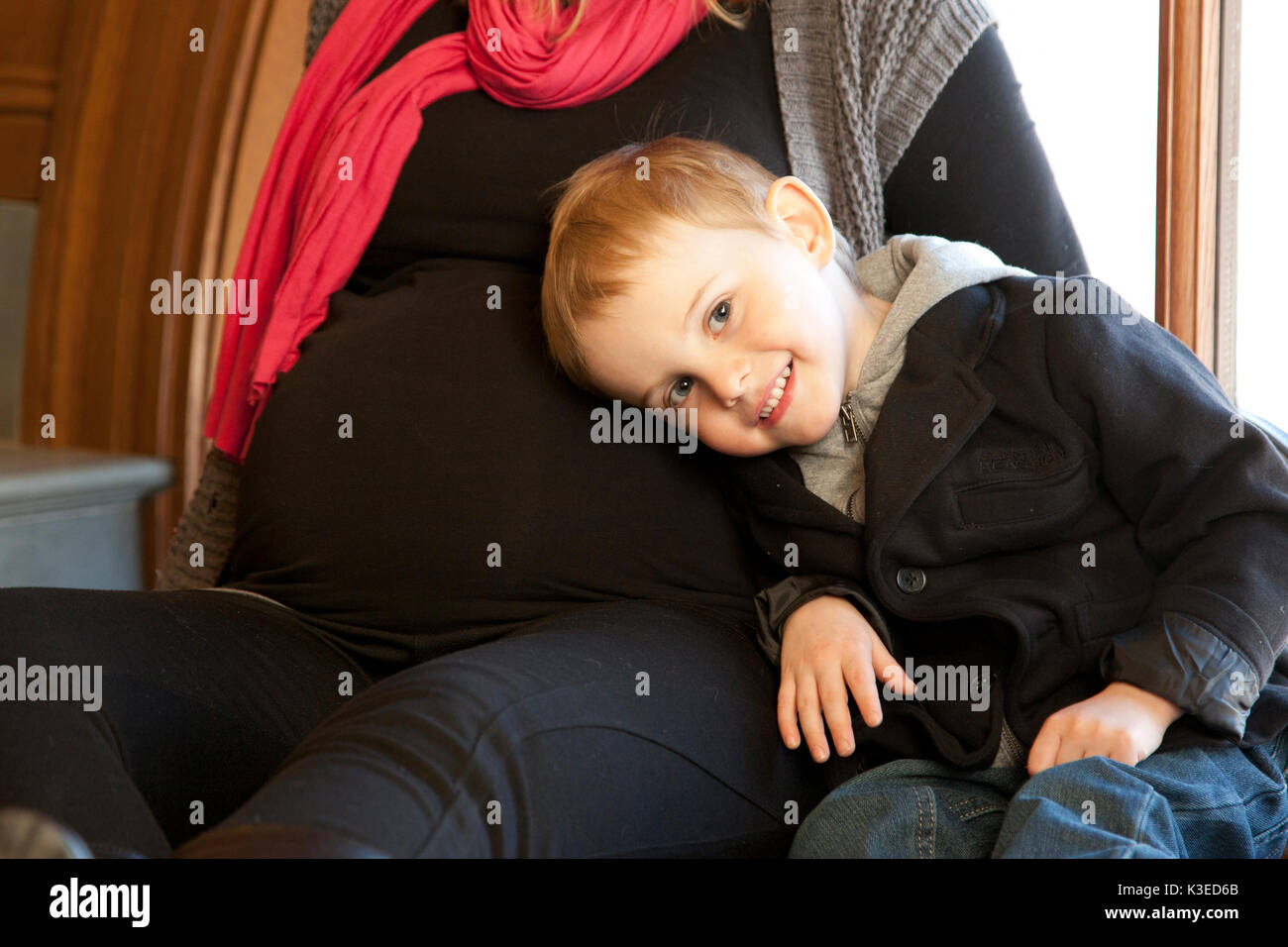 Heureux preschool boy resting head contre l'estomac de mère enceinte à l'écoute de bébé. Banque D'Images