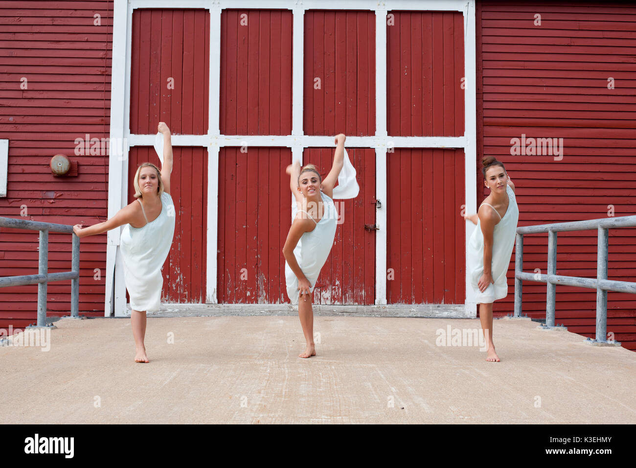 Trois sœurs en robes blanches dansant sur une terrasse en bois. Banque D'Images