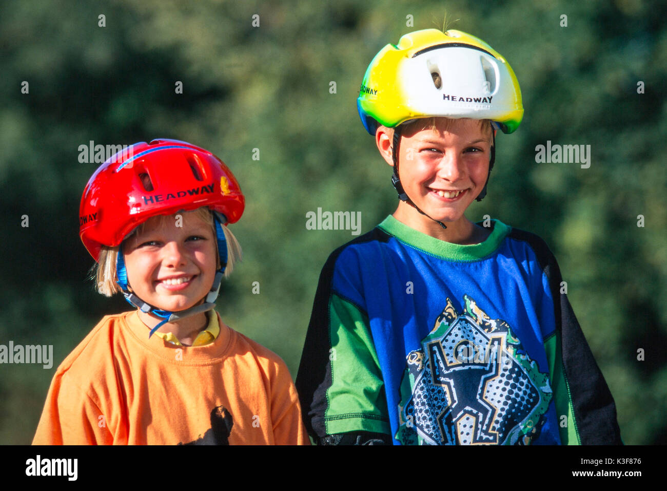 Un petit rire fille et garçon avec casque de vélo Banque D'Images