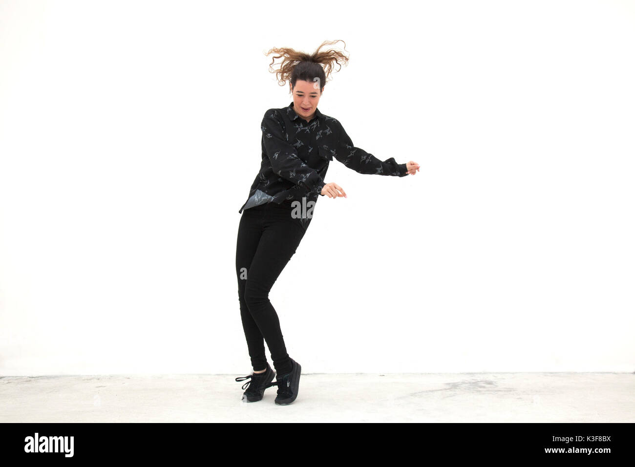 Jeune femme adulte dansant sur fond blanc Banque D'Images