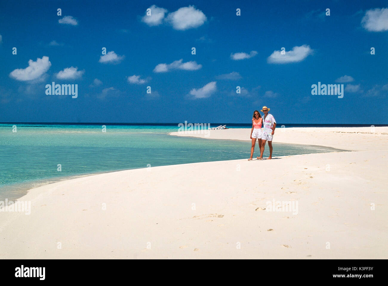 Couple se présente pour une promenade dans les bras sur une plage solitaire (les Maldives) Banque D'Images