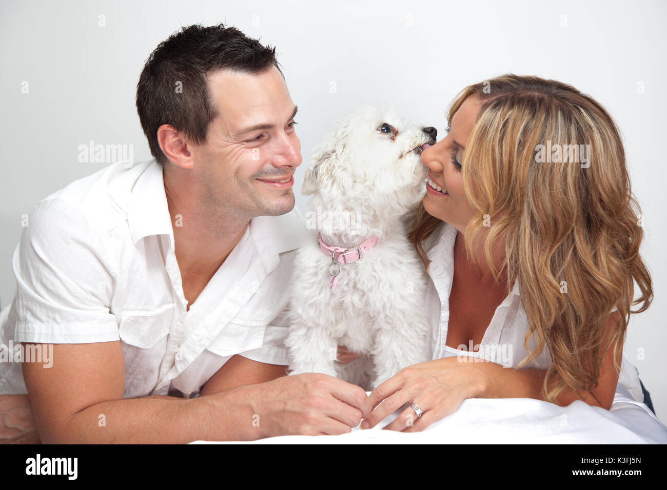 Couple heureux avec de jeunes animaux, chien chiot kissing woman. Banque D'Images
